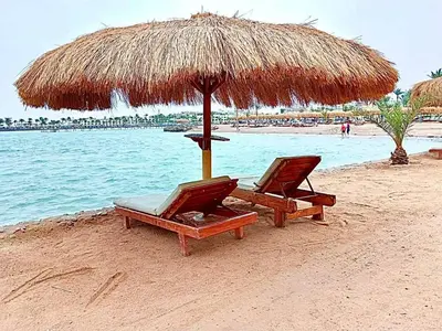 two chairs and an umbrella on a beach at Pearl of Tiba Golden Resort in Hurghada