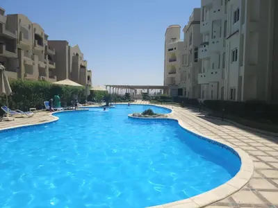 a swimming pool with blue water in front of buildings at 310 el Andalous Apartment in Hurghada