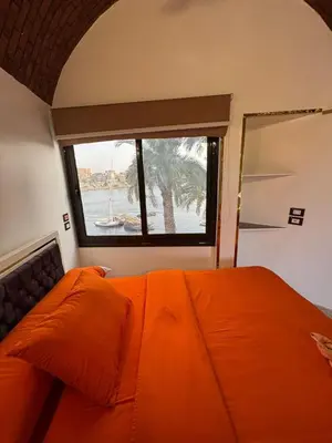 an orange bed in a room with a window at Nubian Dreams guest house 2 in Aswan