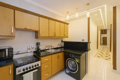 a kitchen with wooden cabinets and a washer and dryer at Omar Apartment in Luxor
