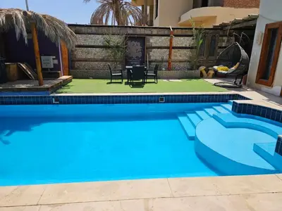 a blue swimming pool with chairs and a table at Silkes Villa in Hurghada
