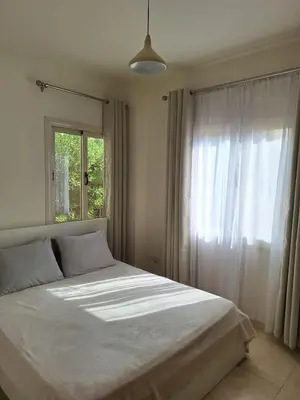 a bedroom with a white bed with a window at Makadi Heights Apartment in Hurghada