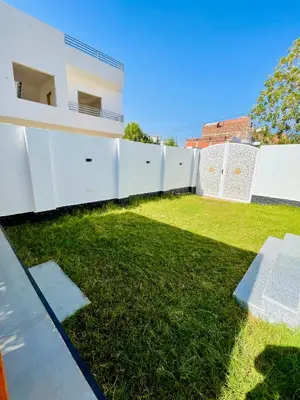 a backyard with a white fence and grass at Quiet Villa in Luxor