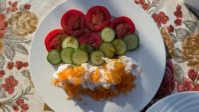 a white plate of food with cucumbers and cheese at Karima house B in Al Aqālitah