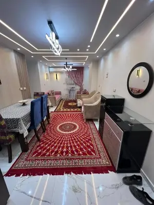 a living room with a table and a red rug at Flat in Nag` el-Ramla