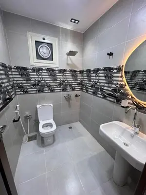 a bathroom with a toilet and a sink and a clock at Flat in Nag` el-Ramla