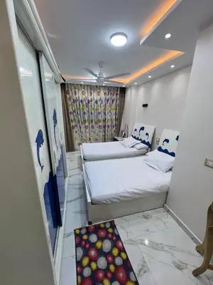 a bedroom with two beds and a rug in it at Flat in Nag` el-Ramla