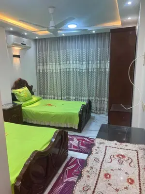 two beds in a room with green sheets and a window at Aswan in Nag` el-Ramla