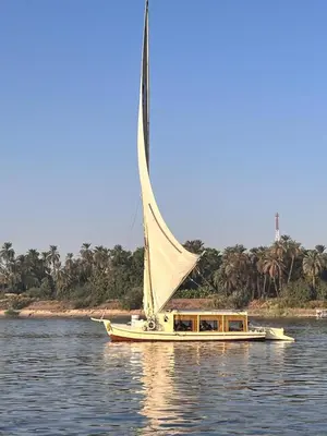 a boat with a large sail on the water at Nile SE Felucca nile cruise private tour in Naj‘ al ‘Amrāb