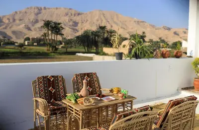 a table and chairs on a patio with mountains in the background at Akhet House in Luxor