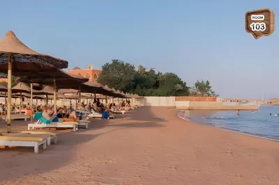 a beach with people sitting on chairs and umbrellas at Touristic centre beach2 in Hurghada