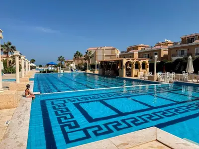 a pool at a resort with a person sitting next to it at Luxurious Apartment in Selena Bay - Private Beach, 5 Pools and Kite Surfing in Hurghada