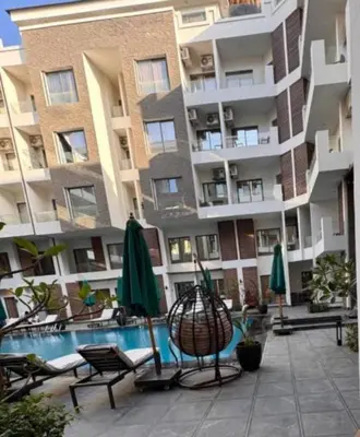 an apartment building with a pool and chairs and umbrellas at 422batthepavillionImperialHurghada in Hurghada