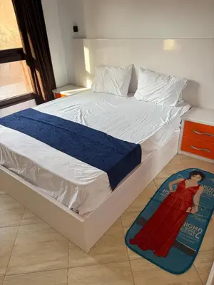 a white bed with a blue blanket on the floor at Modern 1BR Seaside Apartment C1 in Turtles Beach in Hurghada
