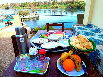 a table with plates of food and fruit on it at Shellaly Ca Nubian Guest2 House in Jazīrat Salūjah