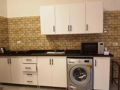 a kitchen with white cabinets and a washing machine at Malika House in Luxor