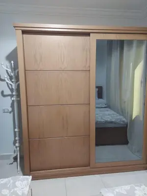 a wooden cabinet with a mirror in a bedroom at Hurghada Apartment with pool in Hurghada