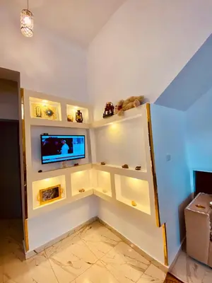 a living room with a tv on a wall at Alena guest house in Jazīrat al ‘Awwāmīyah