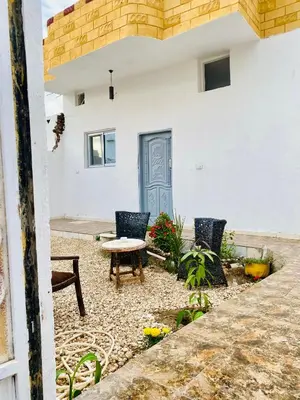 a patio with chairs and a table in front of a building at Alena guest house in Jazīrat al ‘Awwāmīyah