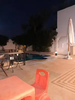 a patio with a table and a chair and an umbrella at Private villa with swimming pool in Hurghada