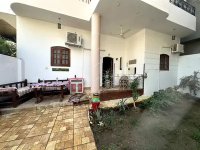 a white house with a porch and a patio at Garden Level Oasis Near Nile in Luxor