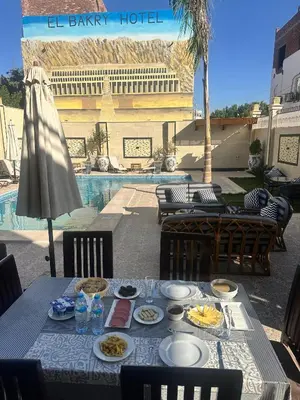 a table with plates of food on it next to a pool at Elbakry Hotel Luxor in Luxor