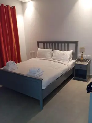 a bedroom with a bed with white sheets and a red curtain at Charment Chalet Somabay in Hurghada