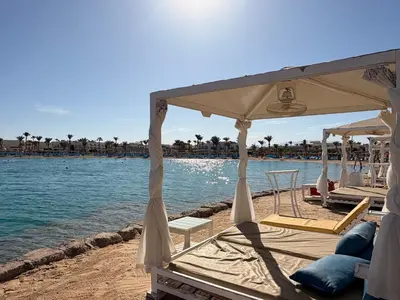 a beach with chairs and umbrellas next to the water at Casa Seherezade in Hurghada