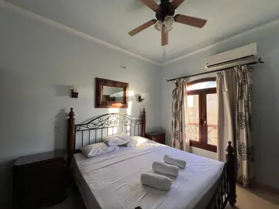a bedroom with a bed with white sheets and a ceiling fan at Waterfront Sabina I 4Bdr Retreat - Heated Pool in Hurghada
