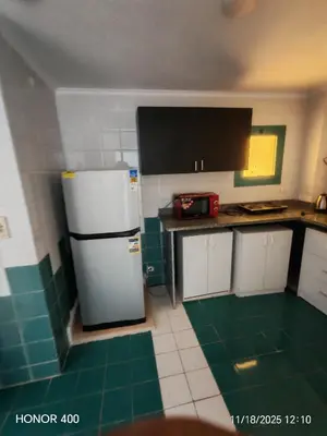 a kitchen with a white refrigerator and green tiles at Elixir Two Bed Rooms in Hurghada