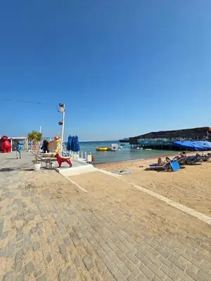 a beach with a pier and people laying on the sand at Pool Dream Hurghada in Hurghada