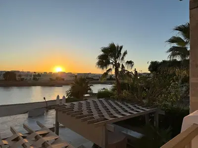 a sunset over a body of water with a wooden deck at The Nest Namaste - El Gouna in Hurghada