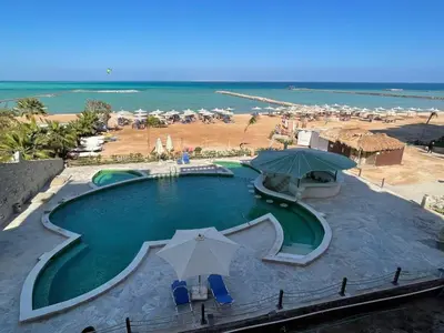 a swimming pool with umbrellas and the beach at Turtle beach resort in Hurghada