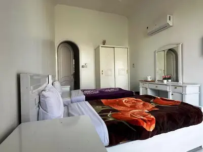 a bedroom with two beds and a table and mirrors at Villa Shanhouri Nile View in Luxor