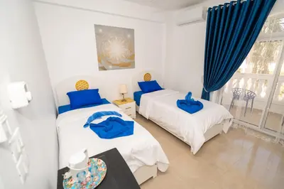 two beds in a bedroom with blue pillows at Home of ISIS in Luxor