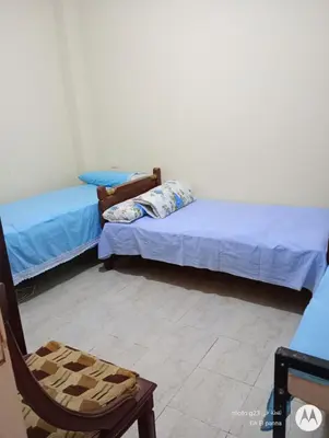 a room with two beds and a chair in it at بيت فرح in Nag` el-Fuqâhi