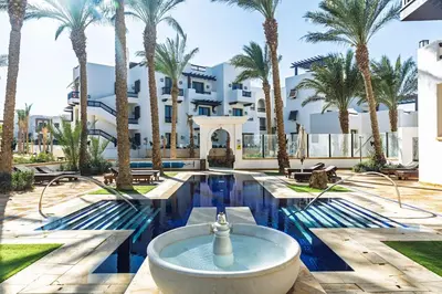 a swimming pool with a fountain in front of a building at Dreamy gateway in Ancient Sands in Hurghada