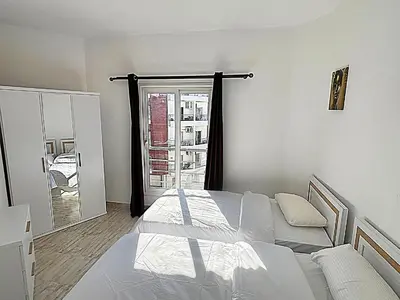 a white bedroom with a bed and a window at Aqua palms in Hurghada