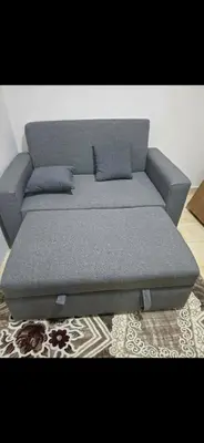 a gray couch with two pillows on a rug at Al helal in Hurghada