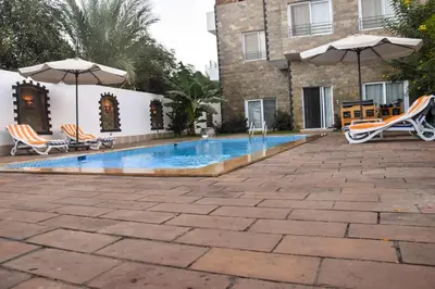 a swimming pool with chairs and umbrellas next to a building at Quiet Corner Apartment in Luxor