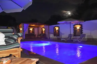a swimming pool at night with chairs and an umbrella at Quiet Corner Apartment in Luxor