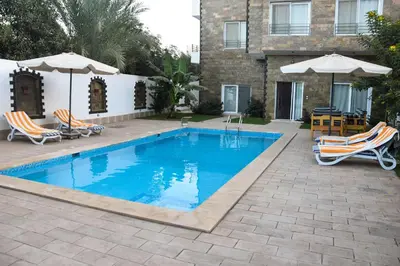 a swimming pool with chairs and umbrellas next to a house at Quiet Corner Apartment in Luxor
