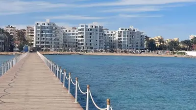 a wooden boardwalk leading to a beach with tall buildings at Amazing studio in Scandic resort in Hurghada