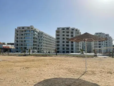 a umbrella on the beach with buildings in the background at Amazing studio in Scandic resort in Hurghada
