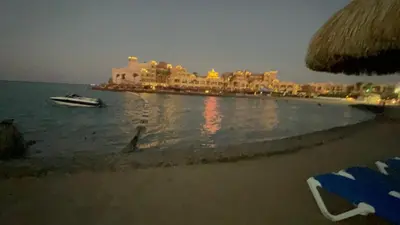a beach with a resort and a boat in the water at Pause by The Sea Hurghada, Stay, Relax, Repeat in Hurghada