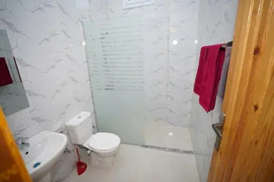 a white bathroom with a toilet and a sink at Astralis Hotel in Al Aqālitah