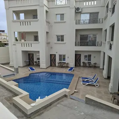 an apartment with a swimming pool and a building at Magawish Studio #3 with pool view in Hurghada