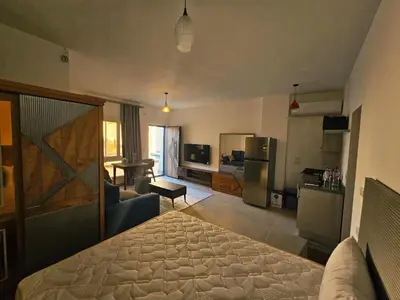 a room with a bed and a kitchen and a living room at Magawish Studio with Pool in Hurghada