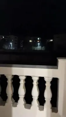 a white railing with a view of a city at night at Moon Apartment Hurghada in Hurghada