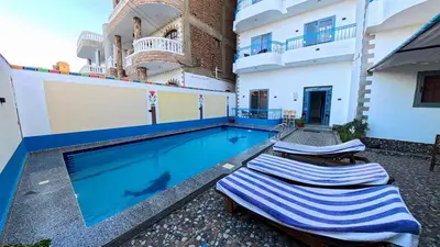 a swimming pool with two lounge chairs next to a building at Alia House in Luxor